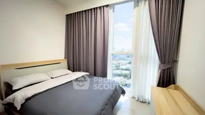Bright bedroom with large window and modern furnishings, offering a serene city view.