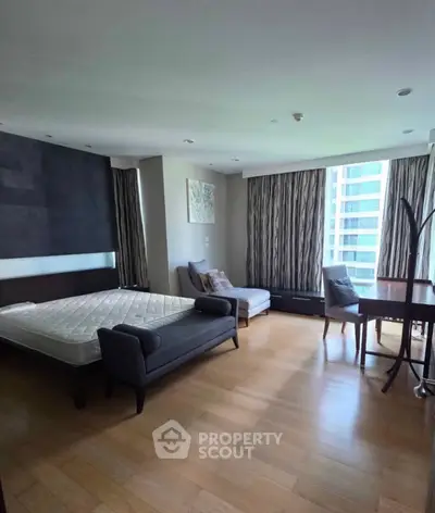 Spacious bedroom with modern furnishings and large windows offering city views.