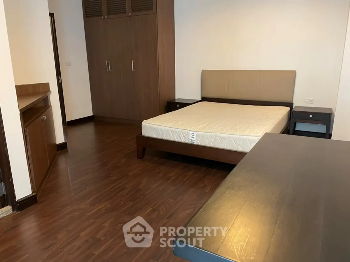 Spacious bedroom with wooden flooring and modern furniture in a stylish apartment.