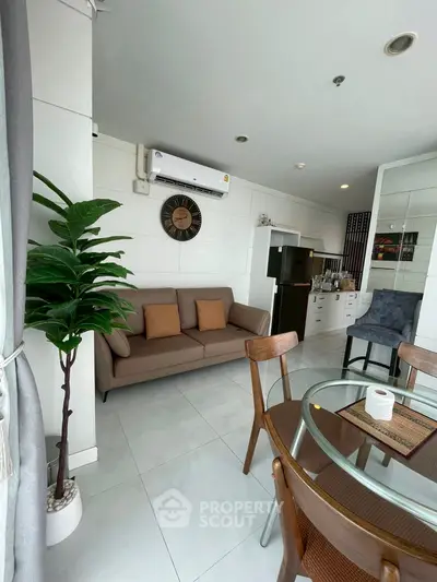 Modern living room with cozy sofa, dining area, and sleek kitchen in open layout.