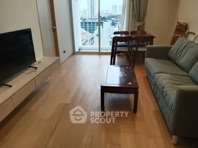 Modern living room with city view, featuring sleek furniture and wooden flooring.