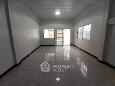 Spacious empty room with tiled flooring and large windows for natural light.