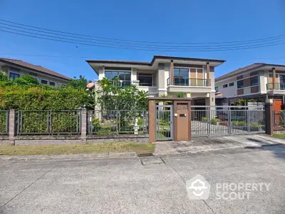 Stunning modern two-story house with lush garden and gated entrance in a serene neighborhood.