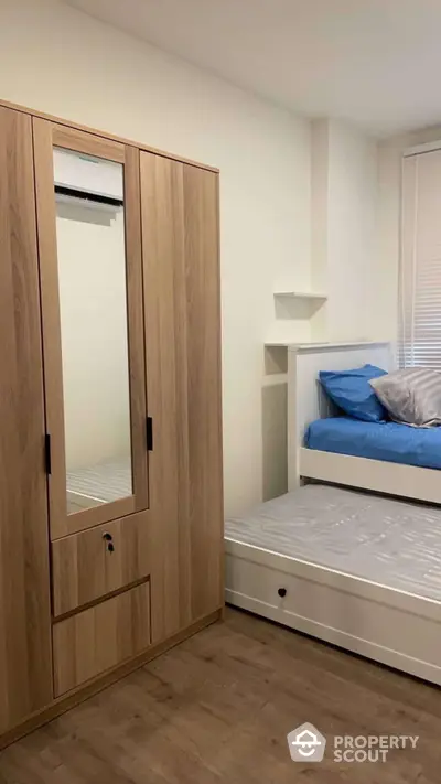 Cozy bedroom with wooden wardrobe and pull-out bed, ideal for compact living spaces.