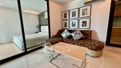 Modern living room with stylish sofa and glass partition leading to cozy bedroom.