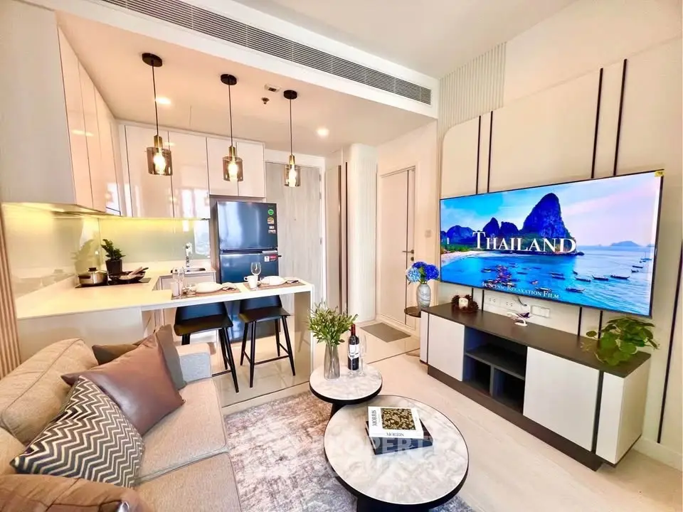 Modern living room with open kitchen, stylish decor, and large TV display.