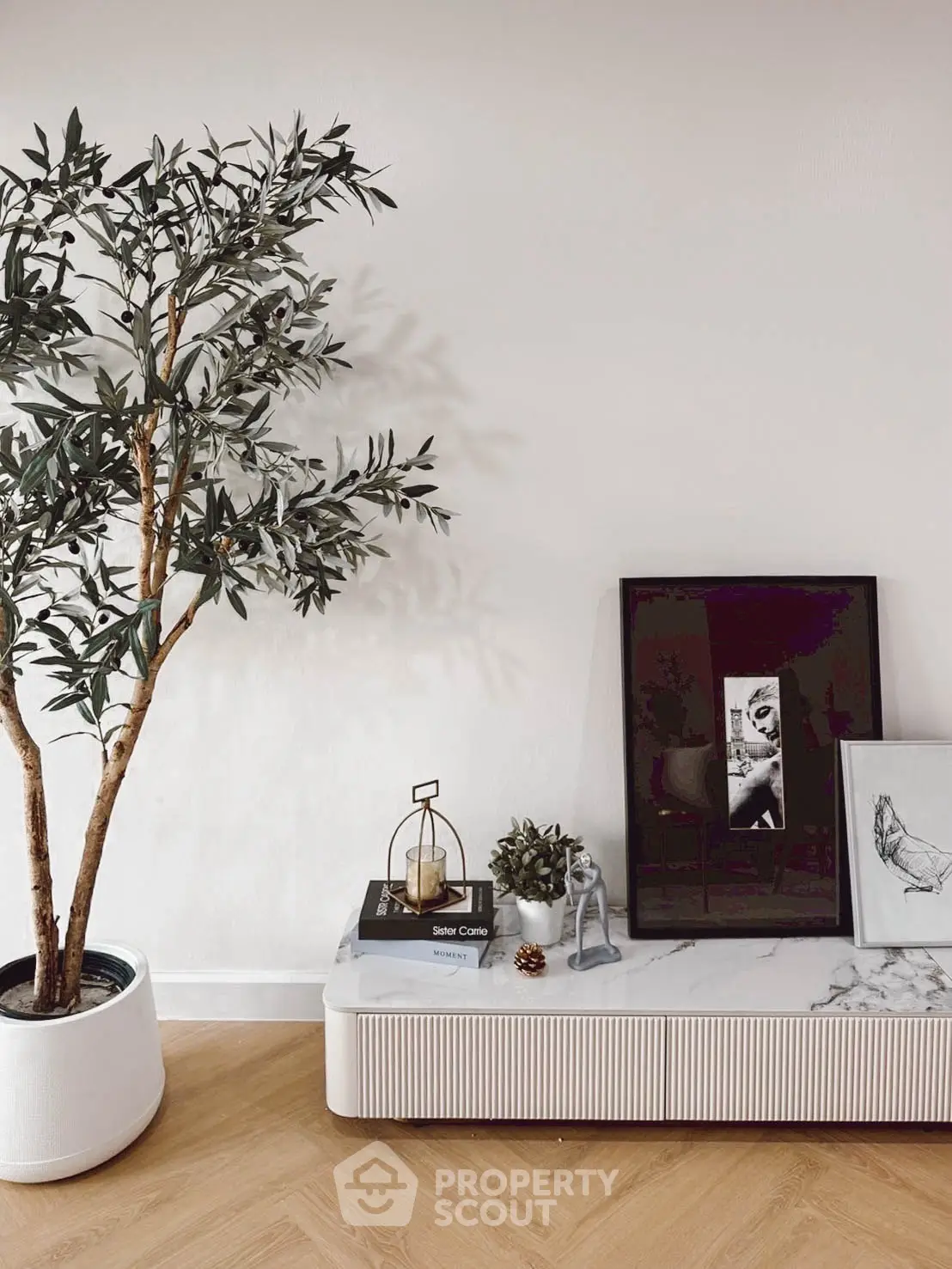 Stylish modern living room corner with potted plant and decor on wooden floor.
