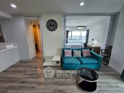 Modern living room with teal sofa, open layout, and city view from window.