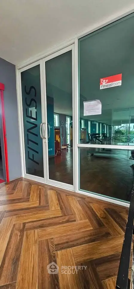 Modern fitness room with glass doors and wooden flooring in a residential building.
