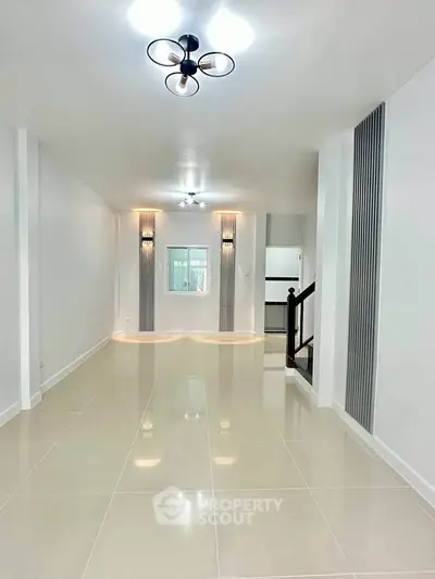 Spacious modern living room with elegant lighting and sleek tile flooring.