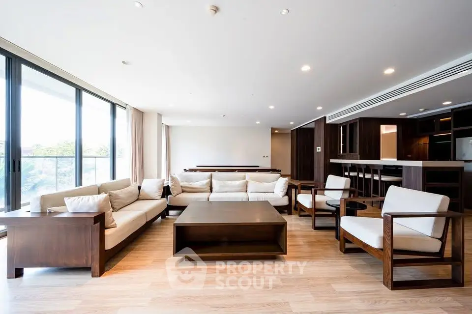 Spacious modern living room with elegant wooden furniture and large windows offering natural light.