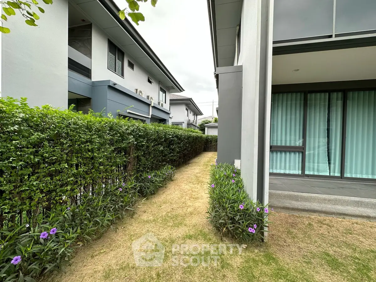 Modern residential exterior with lush garden and pathway, showcasing contemporary architecture and greenery.