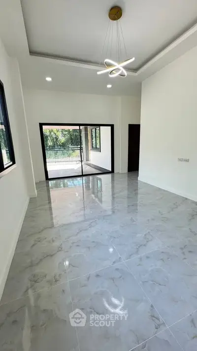Spacious modern living room with elegant lighting and large windows opening to a balcony.