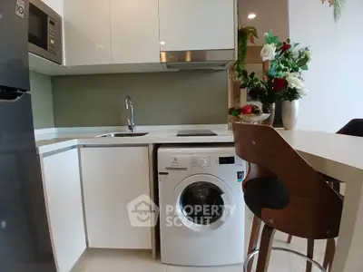 Modern kitchen with sleek appliances and stylish decor, featuring a washing machine and elegant dining area.