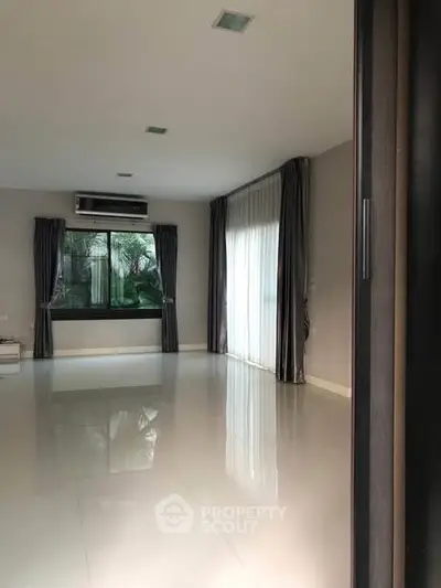 Spacious living room with large windows and modern curtains, perfect for natural light.