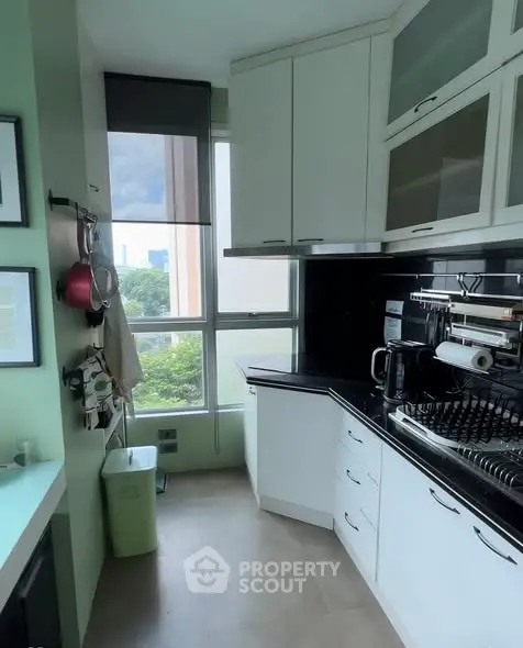 Modern kitchen with sleek cabinets and large window offering city view.