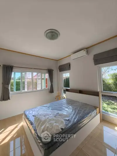 Bright and airy bedroom with large windows and garden view, featuring modern decor and air conditioning.