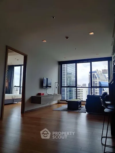 Modern living room with city view, wooden flooring, and stylish furniture in a high-rise apartment.
