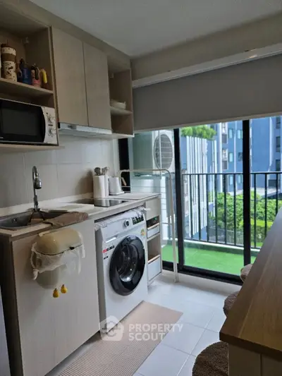 Modern compact kitchen with washing machine and balcony view in urban apartment