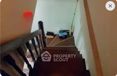 Cozy staircase leading to a lower level with wooden railing and warm lighting.