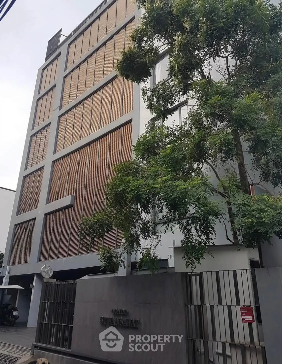 Modern apartment building exterior with sleek design and lush greenery.
