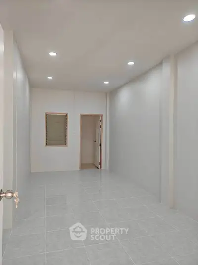 Spacious empty room with tiled flooring and recessed lighting, ideal for customization.