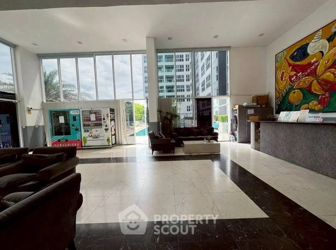Spacious modern lobby with large windows and stylish decor in a luxury building.