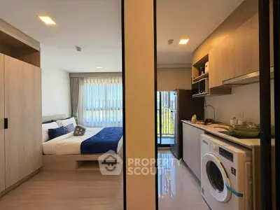Modern studio apartment with cozy bedroom and compact kitchen featuring washing machine and balcony view.