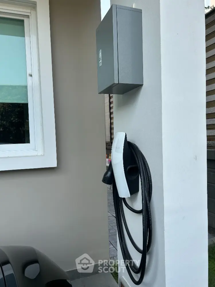 Modern home with eco-friendly electric vehicle charging station installed outside, showcasing sustainability and convenience for green living.
