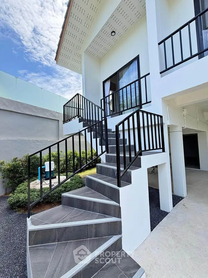 Modern two-story home with sleek exterior staircase and lush landscaping