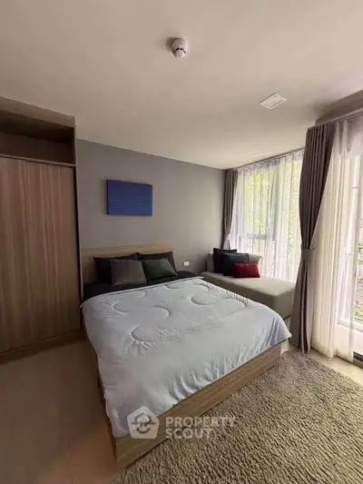 Modern bedroom with large windows and cozy decor in a stylish apartment.
