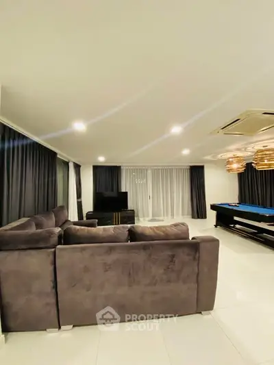 Luxurious living room with plush gray sofa and pool table, perfect for entertainment and relaxation.