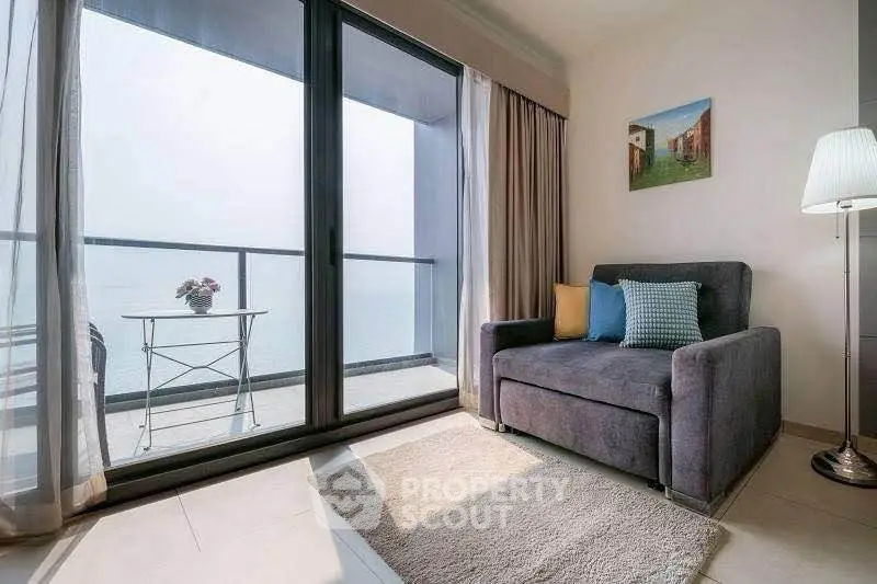 Chic living room with ocean view balcony, cozy seating, and elegant decor.