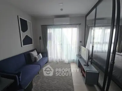 Modern living room with blue sofa, large window, and mirrored wardrobe