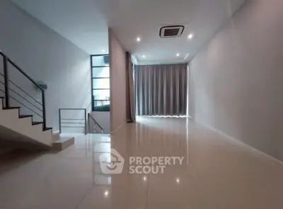 Spacious modern living room with sleek staircase and large windows