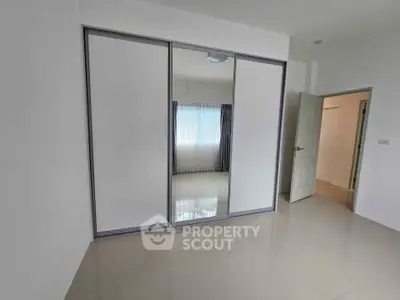 Spacious bedroom with mirrored sliding closet doors and natural light