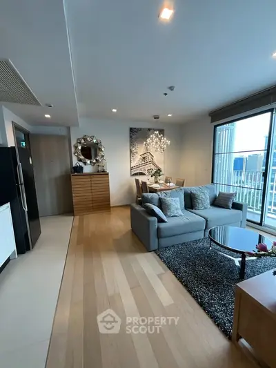 Modern living room with stylish decor and large windows offering natural light and city views.