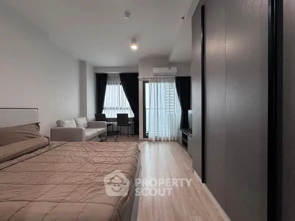 Modern studio apartment with cozy bedroom and living area, featuring large windows and stylish decor.