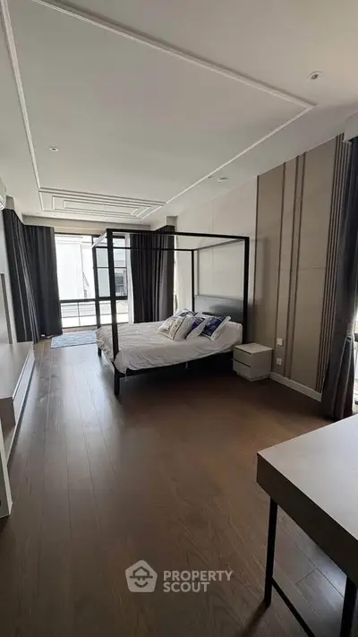 Luxurious bedroom with elegant four-poster bed and floor-to-ceiling windows in modern apartment.