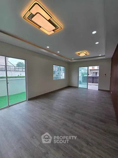 Spacious modern living room with stylish ceiling lights and large windows for natural light.