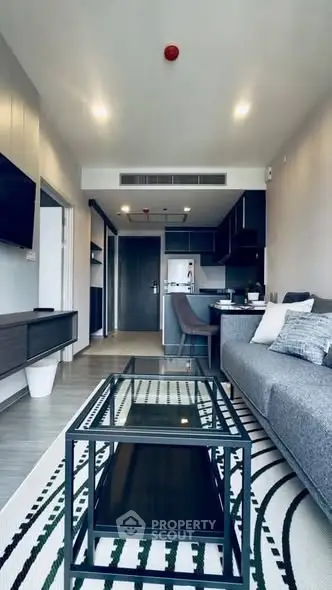 Modern living room with sleek furniture and open kitchen layout in a stylish apartment.