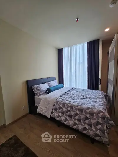 Modern bedroom with stylish decor and large window offering natural light.
