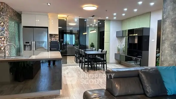 Modern open-plan living room with sleek kitchen and dining area, featuring contemporary decor and stylish lighting.