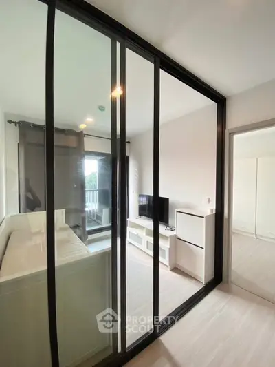 Modern living room with glass partition and sleek furniture in a bright apartment.