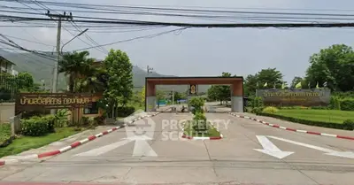 Gated entrance of a residential community with lush greenery and clear signage.
