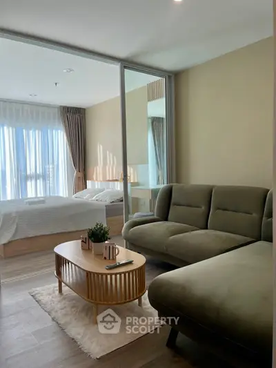 Modern living room with cozy sofa and stylish coffee table, adjacent to a bright bedroom with natural light.