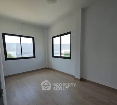 Spacious empty room with large windows and wooden flooring, perfect for customization.