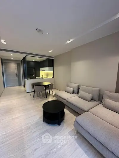 Modern living room with open kitchen, stylish furniture, and sleek design in a contemporary apartment.