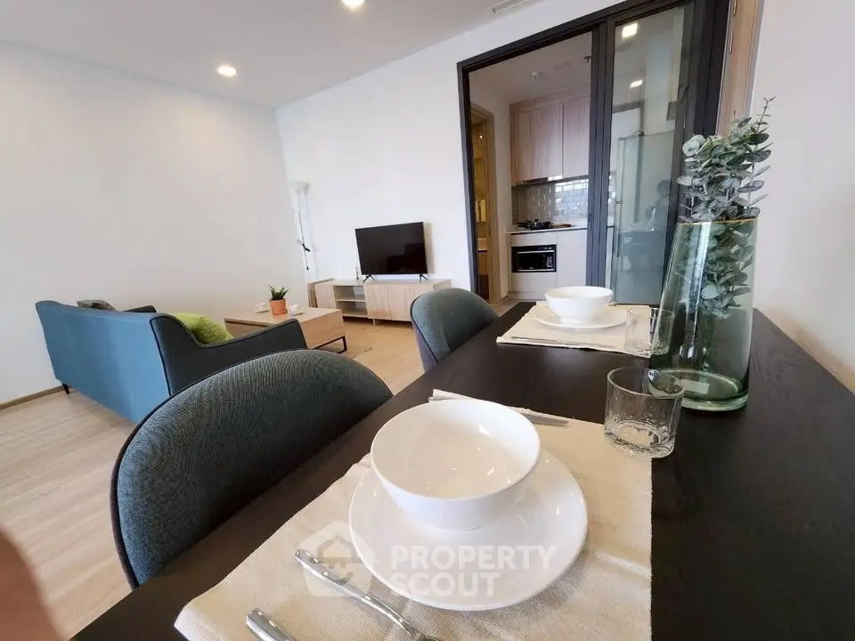 Modern open-plan living room with dining area and kitchen, featuring stylish decor and natural light.