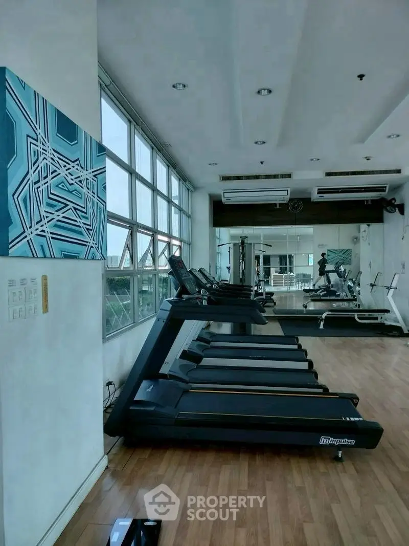 Modern gym with treadmills and large windows offering natural light.